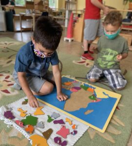 Two preschool aged boys work together on a colorful puzzle map.